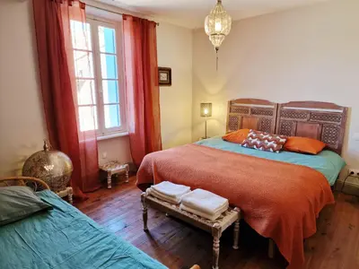 a bedroom with two beds and a couch and windows at L'Orée de la cité in Carcassonne