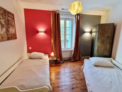 two beds in a room with a red wall at L'Orée de la cité in Carcassonne