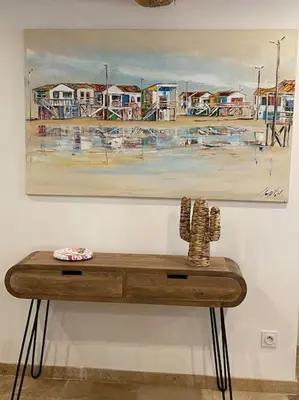 a painting hanging on a wall with a wooden table at Maison Marceau Gruissan in Gruissan