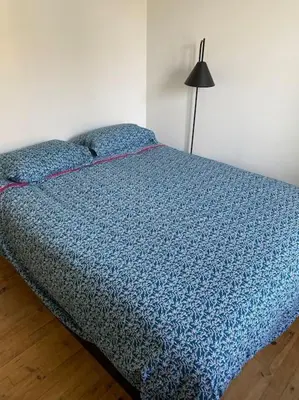 a bed with a blue comforter in a bedroom at Maison Marceau Gruissan in Gruissan