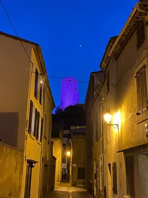 an alley with a pink tower in the background at Maison Marceau Gruissan in Gruissan