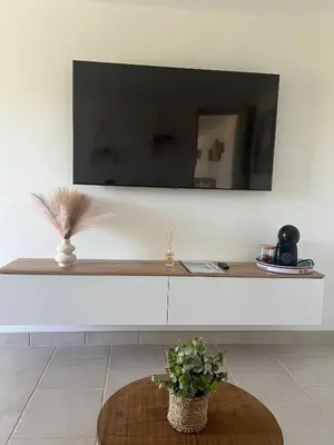 a living room with a table and a tv on a wall at Pavillon T2 climatisé in Villefranche-de-Lauragais