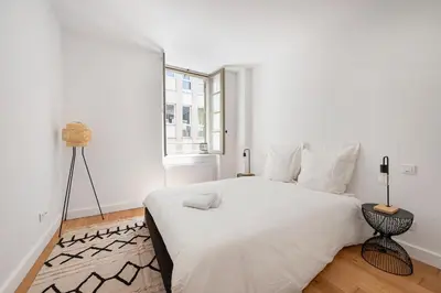 a white bedroom with a white bed and a window at Les Colonnes - T3 - Bastide in Carcassonne