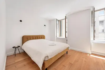 a white bedroom with a bed and two windows at Les Colonnes - T3 - Bastide in Carcassonne