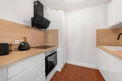 a kitchen with white cabinets and a black oven at Les Colonnes - T3 - Bastide in Carcassonne