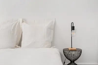 a bed with white sheets and a side table with a lamp at Les Colonnes - T3 - Bastide in Carcassonne