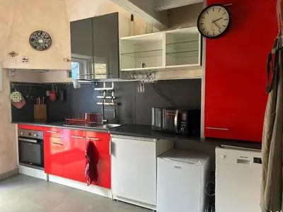 a kitchen with red cabinets and a clock on the wall at la maison des lauriers rouges in Peyriac-de-Mer