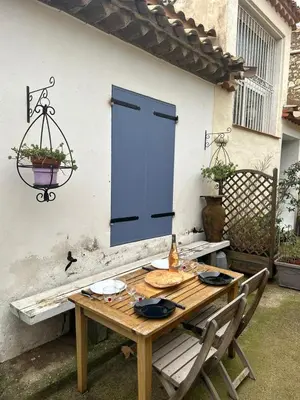 a wooden table with chairs and a blue door at la maison des lauriers rouges in Peyriac-de-Mer