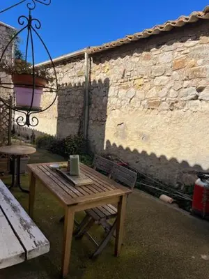 a wooden table and a chair next to a building at la maison des lauriers rouges in Peyriac-de-Mer