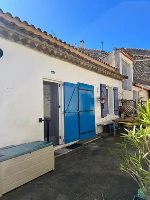 a white house with blue doors and a bench at la maison des lauriers rouges in Peyriac-de-Mer