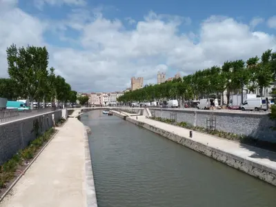 a river in a city with a bridge at La Suite de la Cathédrale in Narbonne