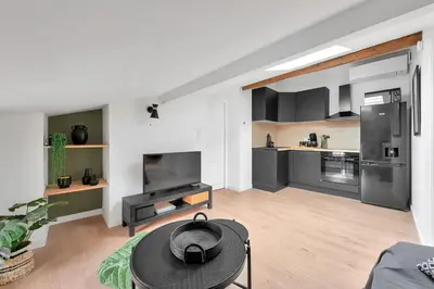a living room with a table and a kitchen at Le Blackwood in Mazamet