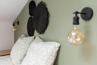 a bedroom with two pillows and a wall with a lamp at Le Blackwood in Mazamet
