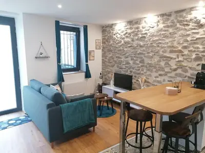 a living room with a blue couch and a table at Charmant appartement de village in Pennautier