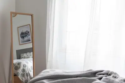 a mirror in front of a bedroom with a bed and a window at Le Polaire in Mazamet