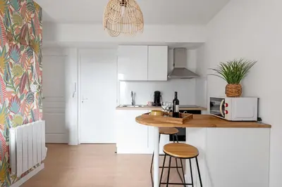 a kitchen with white cabinets and a wooden counter top at Le Tropical : T2 rénové Ambiance Cosy et Colorée in Mazamet