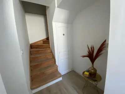 a hallway with stairs and a plant in a vase at Le Tropical : T2 rénové Ambiance Cosy et Colorée in Mazamet