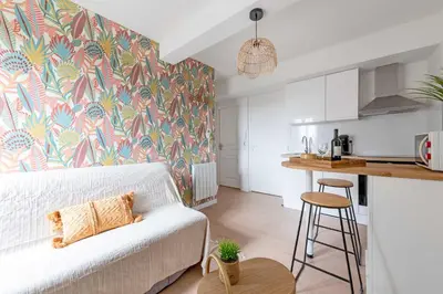 a living room with a white couch and a kitchen at Le Tropical : T2 rénové Ambiance Cosy et Colorée in Mazamet