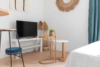 a bedroom with a tv and two stools and a bed at Le Tropical : T2 rénové Ambiance Cosy et Colorée in Mazamet