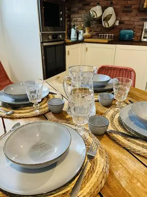 a wooden table with plates and glasses on it at Les cigales - souplex cosy et calme in Mas-Saintes-Puelles