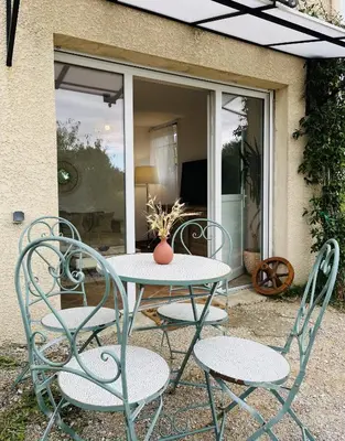 a table and chairs with a vase on top of it at Les cigales - souplex cosy et calme in Mas-Saintes-Puelles