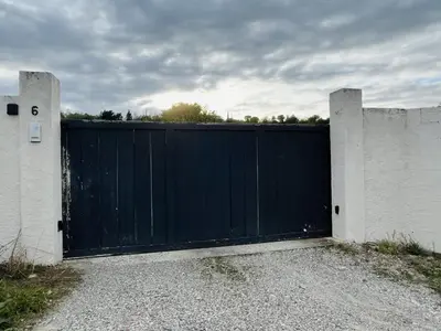 a black gate in front of a white fence at Les cigales - souplex cosy et calme in Mas-Saintes-Puelles