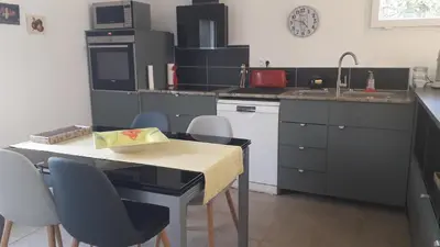 a kitchen with a table and chairs and a sink at L' Abri du Saule in Aussillon