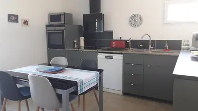 a kitchen with a table and chairs and a sink at L' Abri du Saule in Aussillon