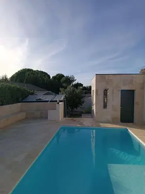 a blue swimming pool in front of a building at Charmant studio avec piscine in Villemoustaussou