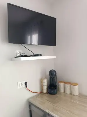 a tv on a wall above a wooden table with barrels at Charmant studio avec piscine in Villemoustaussou
