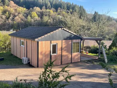 a small wooden shed with a roof on a yard at Cosy Chalet au cœur du Sidobre avec Piscine et Spa in Vabre