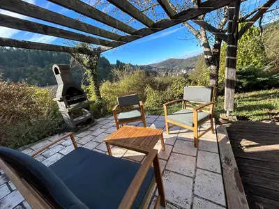 a patio with two chairs and a table and a stove at Cosy Chalet au cœur du Sidobre avec Piscine et Spa in Vabre
