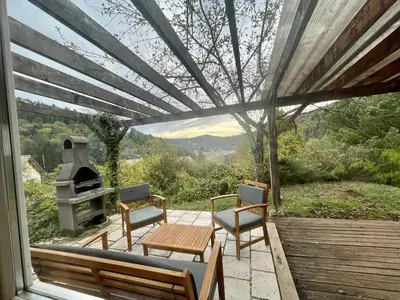 a patio with a table and chairs and a stove at Cosy Chalet au cœur du Sidobre avec Piscine et Spa in Vabre