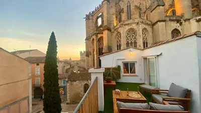 a balcony with chairs and a table in front of a building at L'annexe spa du Tropical Lodge in Narbonne
