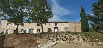 a large house with a stone wall in front of it at Bessire Chambres & table d'hôtes in Belflou
