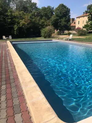 a swimming pool with blue water in a yard at Terrasse avec vue Domaine Viticole in Sallèles-dʼAude