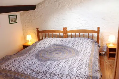 a bedroom with a bed with a blue and white comforter at Panorama Gîtes Certes in Gaudiès