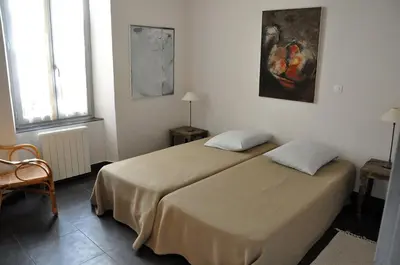 a bedroom with two beds and a painting on the wall at La Maison Du Ruisseau in Conilhac-Corbières