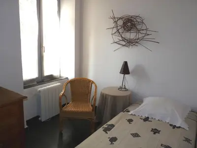 a bedroom with a bed and a chair and a table at La Maison Du Ruisseau in Conilhac-Corbières