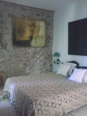 a bedroom with a bed and a stone wall at La Maison Du Ruisseau in Conilhac-Corbières