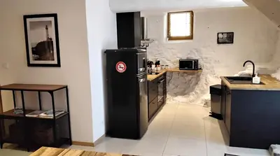a kitchen with a black refrigerator and a counter at Les Remparts in Caudiès-de-Fenouillèdes