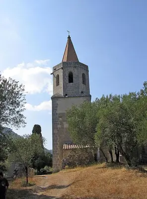 an old building with a tower on a hill with trees at Les Remparts in Caudiès-de-Fenouillèdes