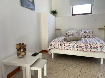 a white bedroom with a bed and a table at Maison au cœur du village de Gruissan in Gruissan