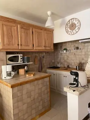 a kitchen with wooden cabinets and a clock on the wall at Maison au cœur du village de Gruissan in Gruissan