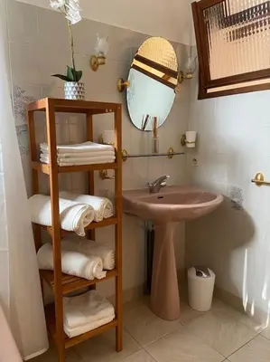 a bathroom with a sink and a shelf with towels at Maison au cœur du village de Gruissan in Gruissan