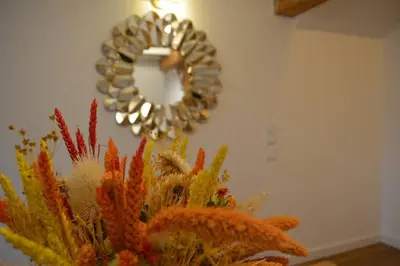 a wreath on a wall with a vase filled with colorful plants at Charmant appartement - proche château cité in Carcassonne