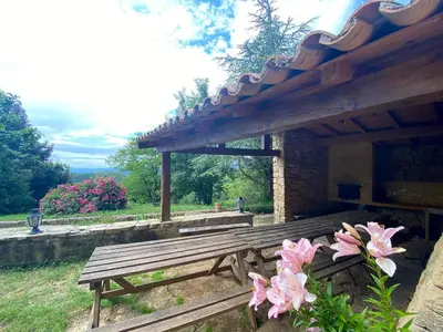 a wooden bench under a pavilion with pink flowers at Maison de campagne à Camps-sur-l'Agly avec vue sur lac in Camps-sur-lʼAgly