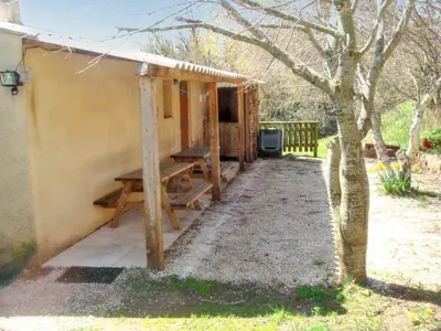 a picnic table under a shed next to a tree at Maison confortable au cœur de la nature près de Camps-sur-l'Agly in Camps-sur-lʼAgly