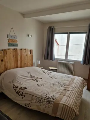 a bedroom with a bed with a wooden headboard and a window at Petite maison au cœur du village in Cessenon
