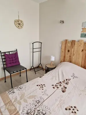 a bedroom with a bed and a chair and a clock at Petite maison au cœur du village in Cessenon